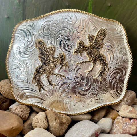 Montana Silversmiths Belt Buckle with gold-tone fighting roosters, intricate scalloped design, and detailed silver engraving - 1707. Available at Blair's Western Wear, Marble Falls, TX.