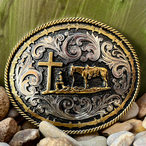 Montana Silversmiths Oval Buckle in silver and gold, spiritual motif with praying cowboy at the cross - A543. Available at Blair's Western Wear, Marble Falls, TX.