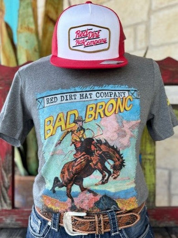 Men's Red Dirt T-Shirt with Graphic of a Cowboy Riding a Bronco with a blue sky in the background with the words "Bad Bronc" on top and a sign that says "Red Dirt Hat Company" - RDHCT104 - BLAIR'S Western Wear located in Marble Falls Tx